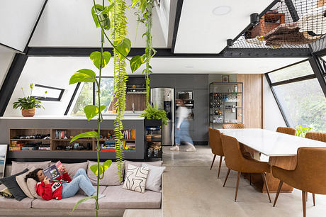 Open, modern living space with lush greenery, industrial-style shelving, and cozy seating.