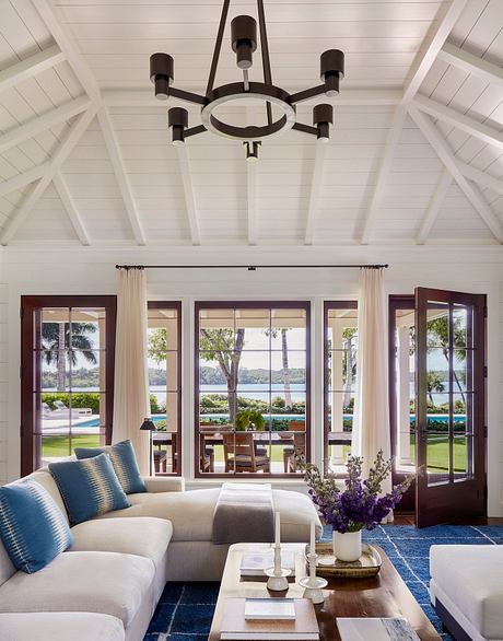 Spacious living room with high-ceiched vaulted ceiling, large windows offering scenic views, and a modern chandelier.