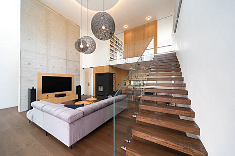Sleek modern living space with concrete walls, floating wood stairs, and globe pendant lights.