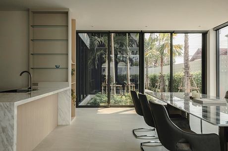 A modern, spacious kitchen with glass walls overlooking a lush, tropical garden.