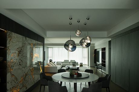 Spacious, modern living room with sleek lighting fixtures, marble walls, and round dining table.