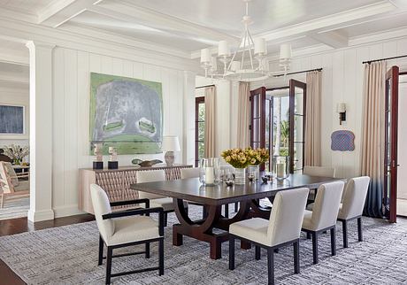 Elegant dining room with high ceilings, large artwork, and a dark wood dining table.