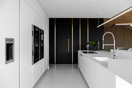 Sleek modern kitchen with bold black and white color scheme, clean lines, and built-in appliances.