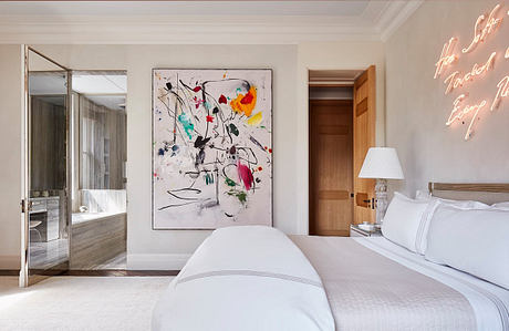 Spacious bedroom with abstract artwork, plush bedding, and modern wooden furnishings.
