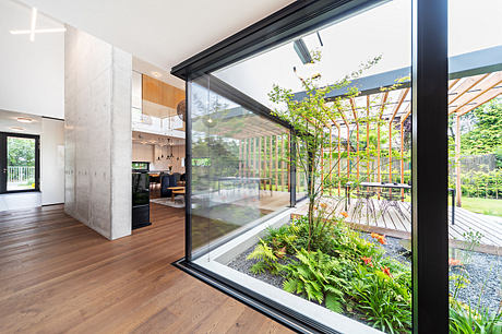 Expansive glass walls open to a lush outdoor garden, blending nature and modern design.