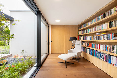 Cozy reading nook with floor-to-ceiling bookshelves, large window overlooking garden.