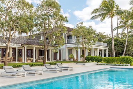 Impressive two-story tropical villa with pool, palm trees, and elegant balconies.