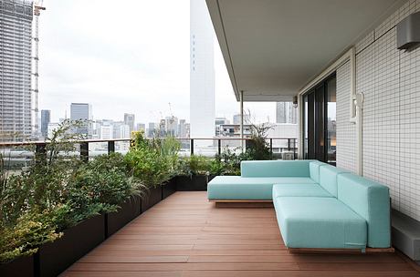 Balcony oasis with lush greenery, modern couch, and scenic city view.