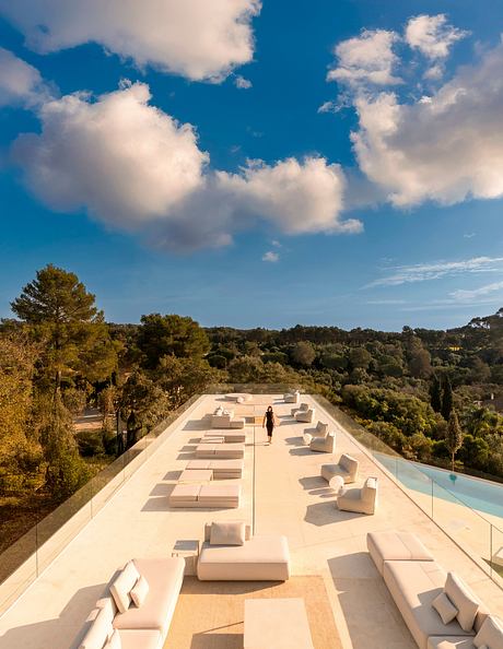Elevated modern outdoor lounge with white furniture and sweeping mountain view.