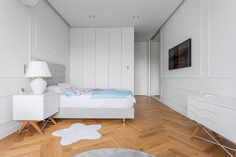 Minimalist bedroom with wood floors, built-in closets, and a gray upholstered bed frame.