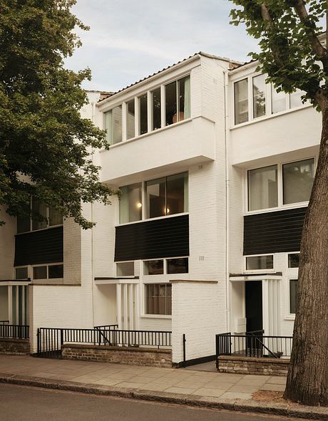 Modernist-style building with contrasting white facade, black balconies, and large windows.