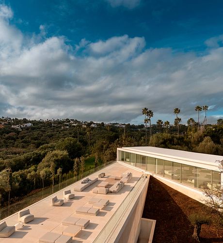 Sleek modern architecture with glass walls overlooking lush green landscape.