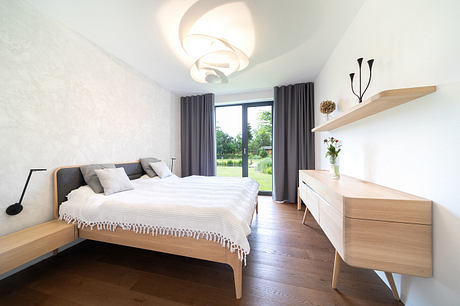 A modern and minimalist bedroom with wooden furniture, curtains, and a stylish light fixture.