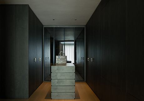 Sleek, minimalist interior with dark wooden built-in cabinets, drawers, and a light-colored floor.