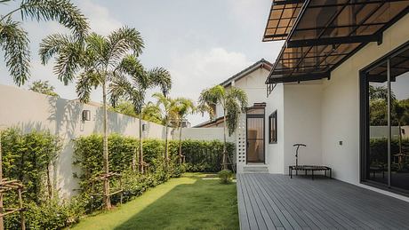 A modern, tropical-inspired home with a spacious outdoor deck, lush foliage, and sleek architectural elements.