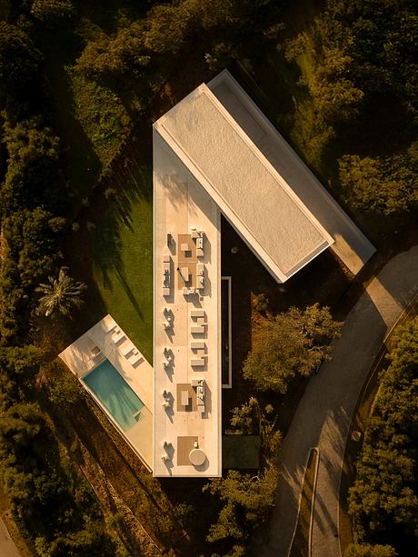 A modern architectural design with angled roof, pool, and surrounding foliage.