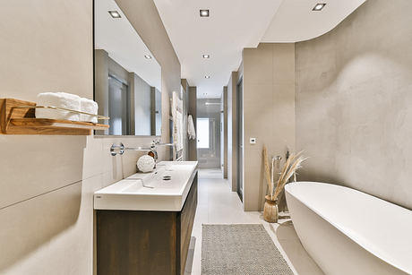 Spacious, minimalist bathroom design with clean lines, wooden accents, and recessed lighting.
